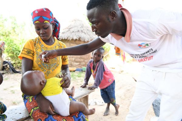 Mother holds baby as he gets his vitamin A drop.