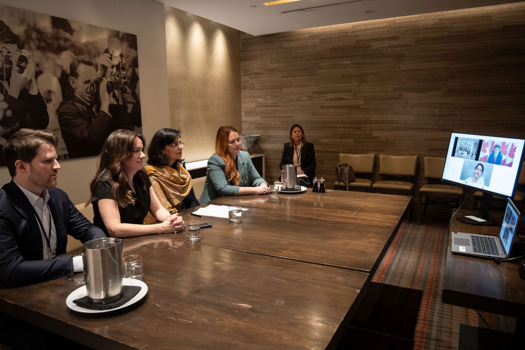 Several people sitting around a large wooden conference table in a meeting.